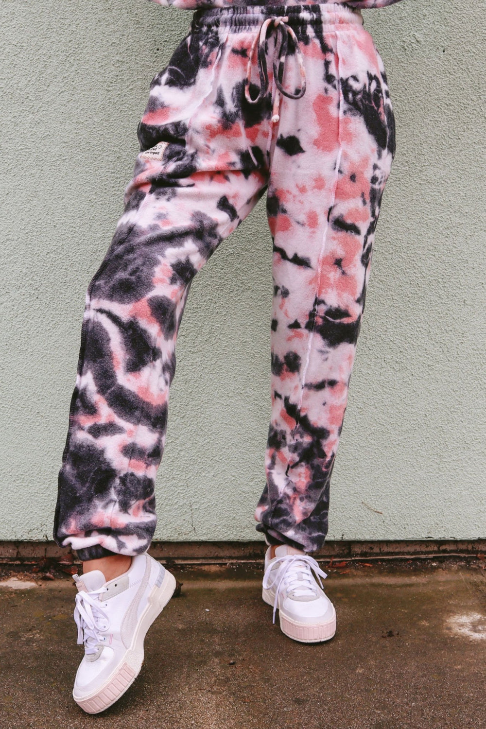 A pair of stylish tie-dye sweatpants featuring a unique blend of blue, pink, and black colors, designed for comfort and leisure.