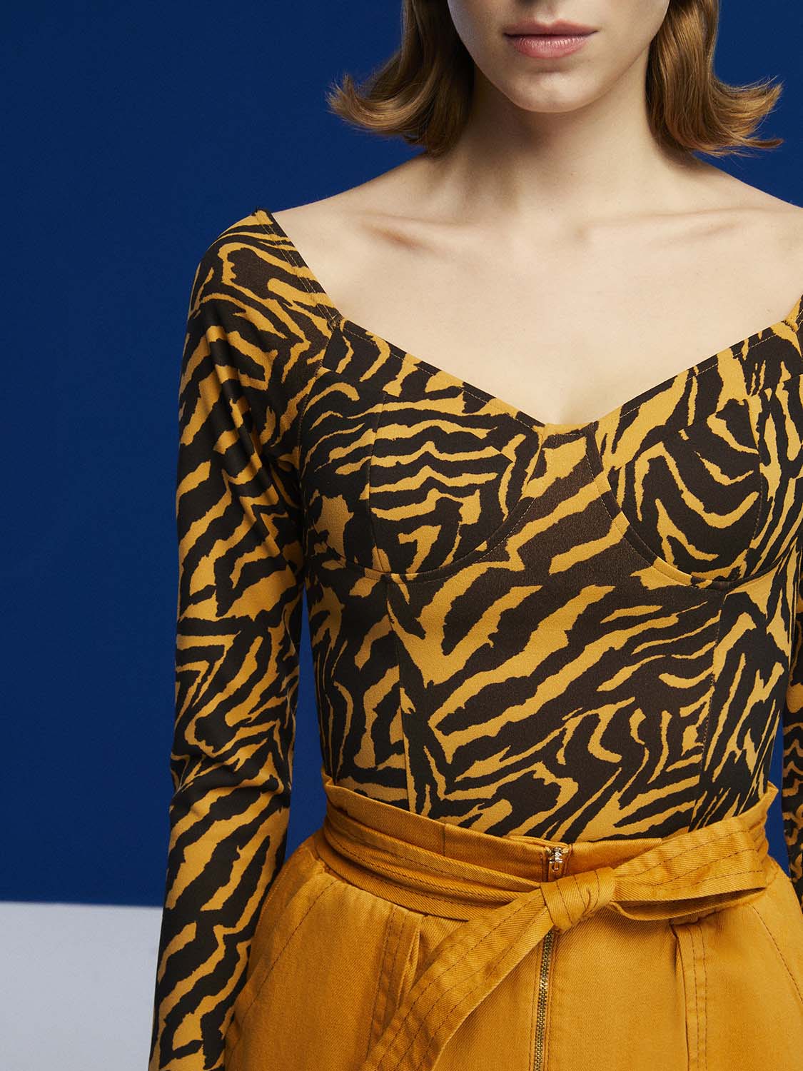 Tiger Print Bodysuit featuring a wide neck, open back, and long sleeves in a warm brown color.