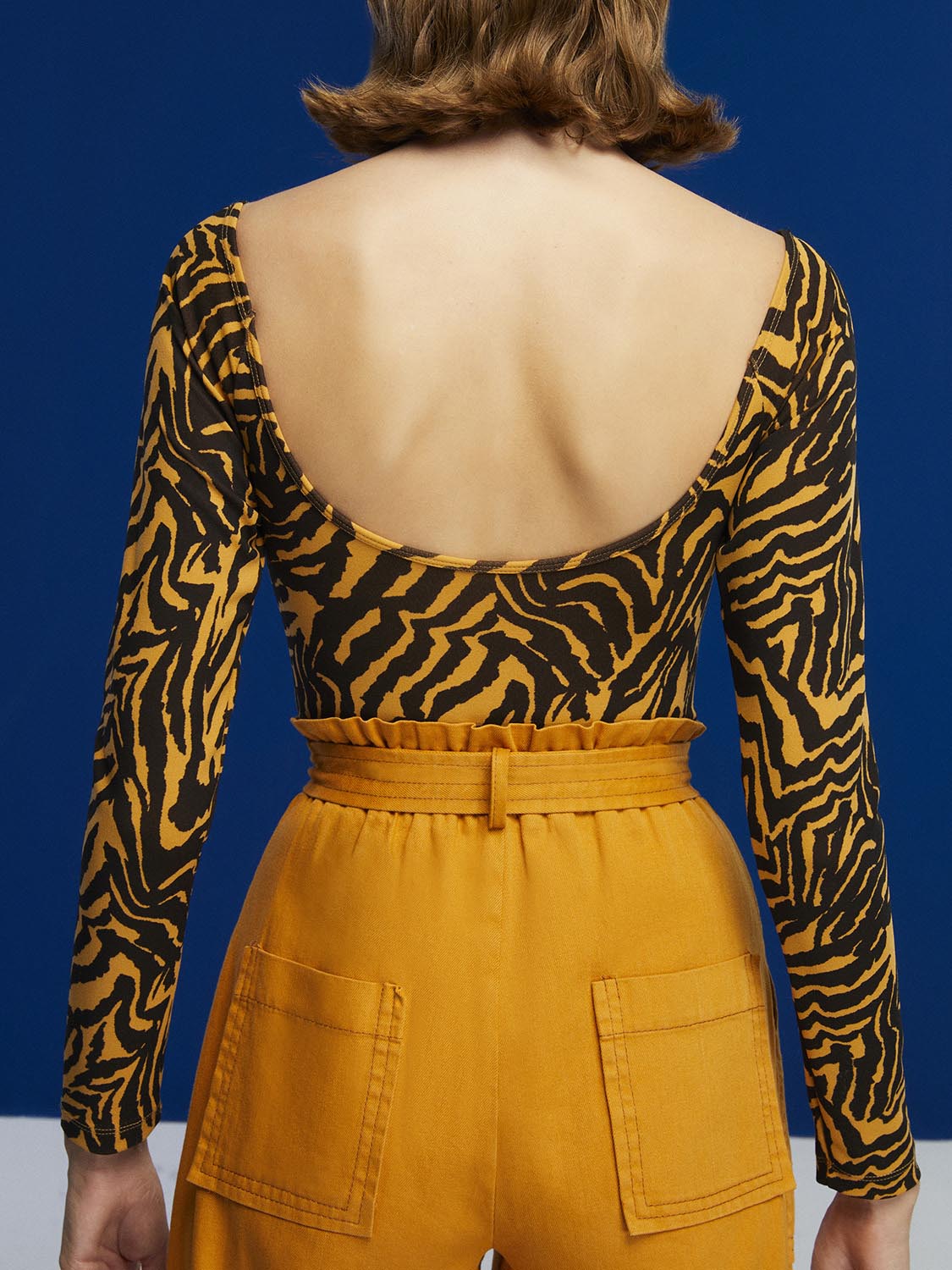 Tiger Print Bodysuit featuring a wide neck, open back, and long sleeves in a warm brown color.