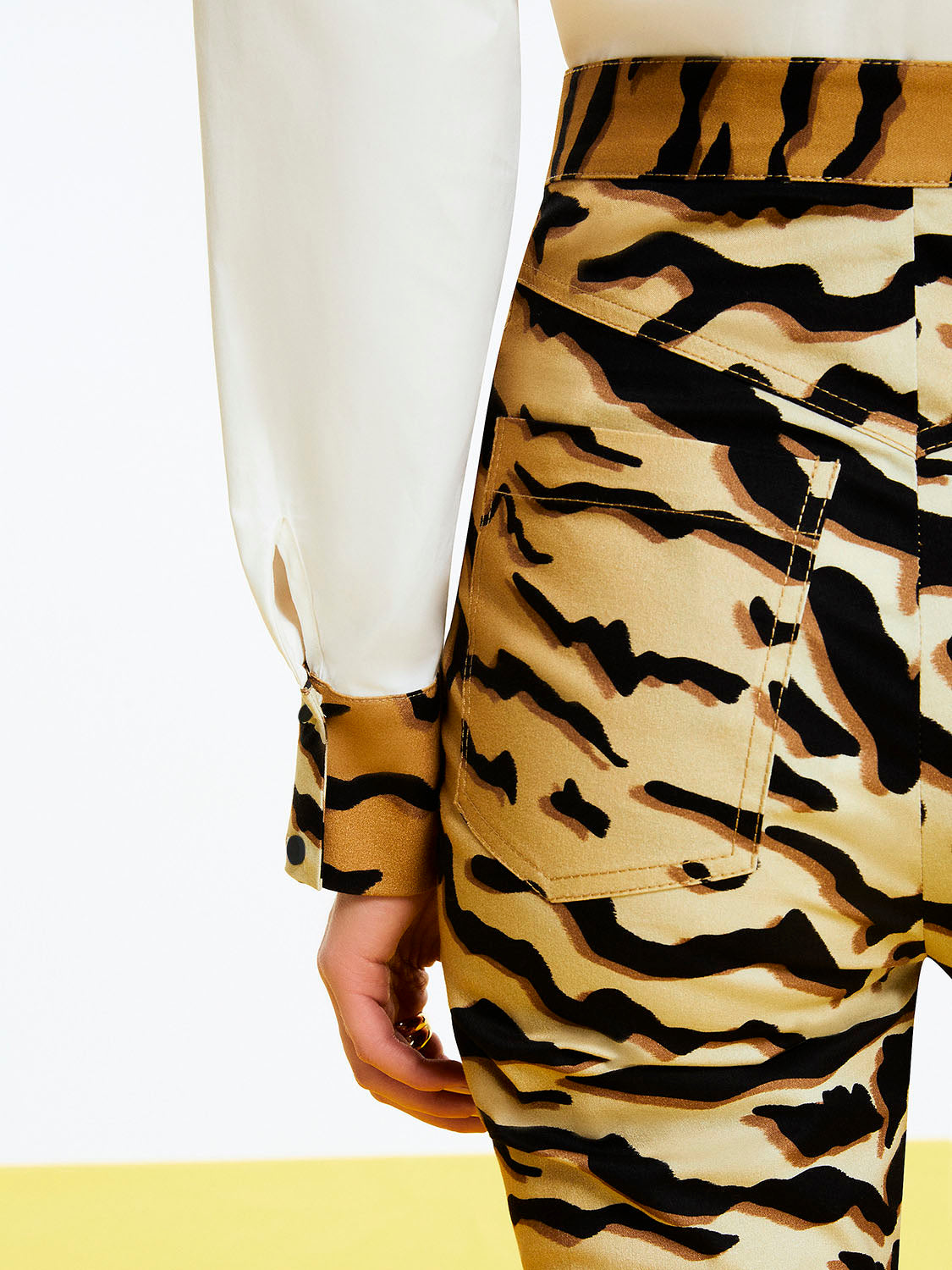 A pair of stylish tiger print high-waisted pants featuring a fitted ankle-length design with hidden zipper detail at the hem.