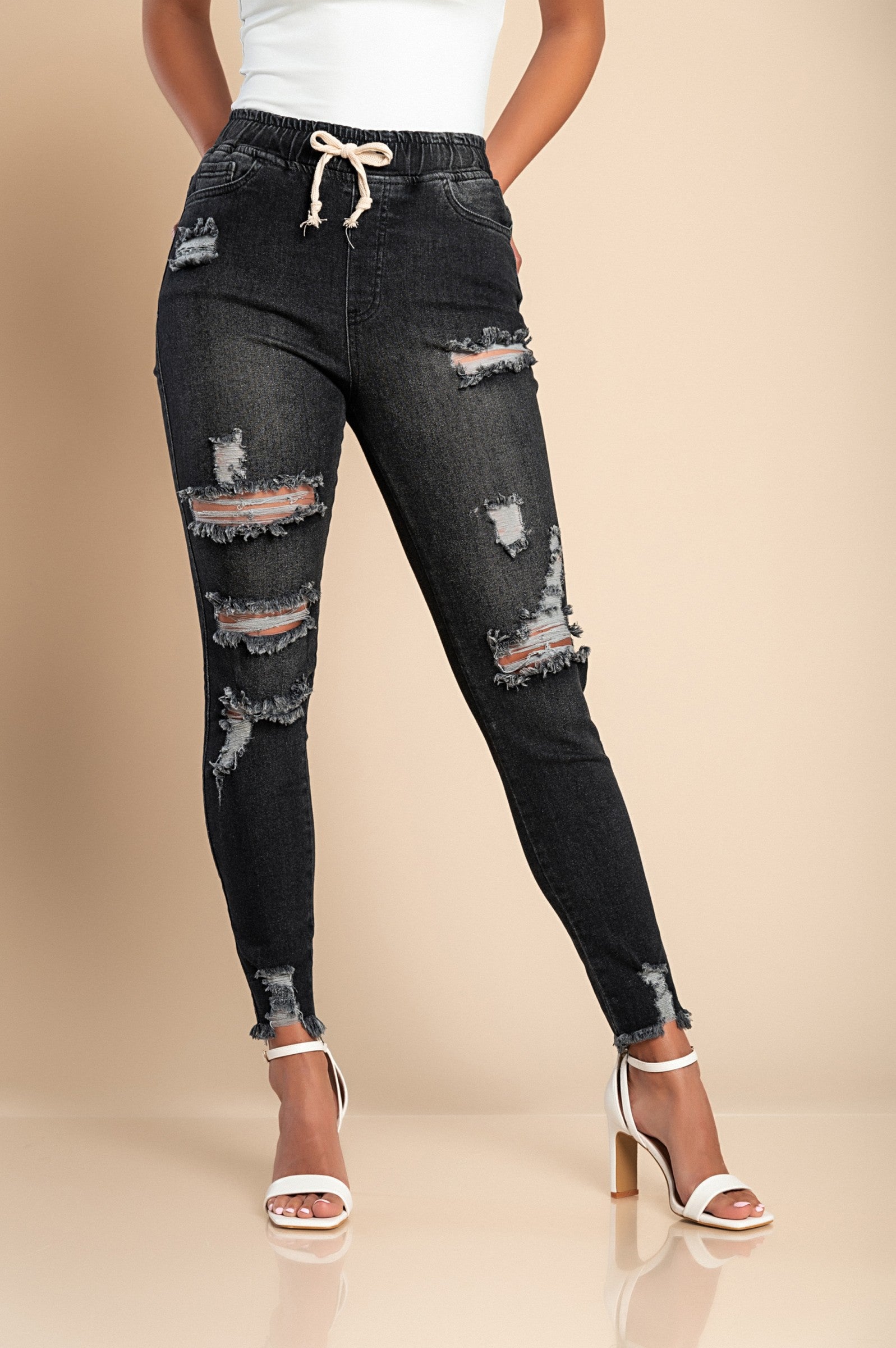 Black tight jeans with high waist and fashionable slits, featuring ripped edges and front and back pockets.