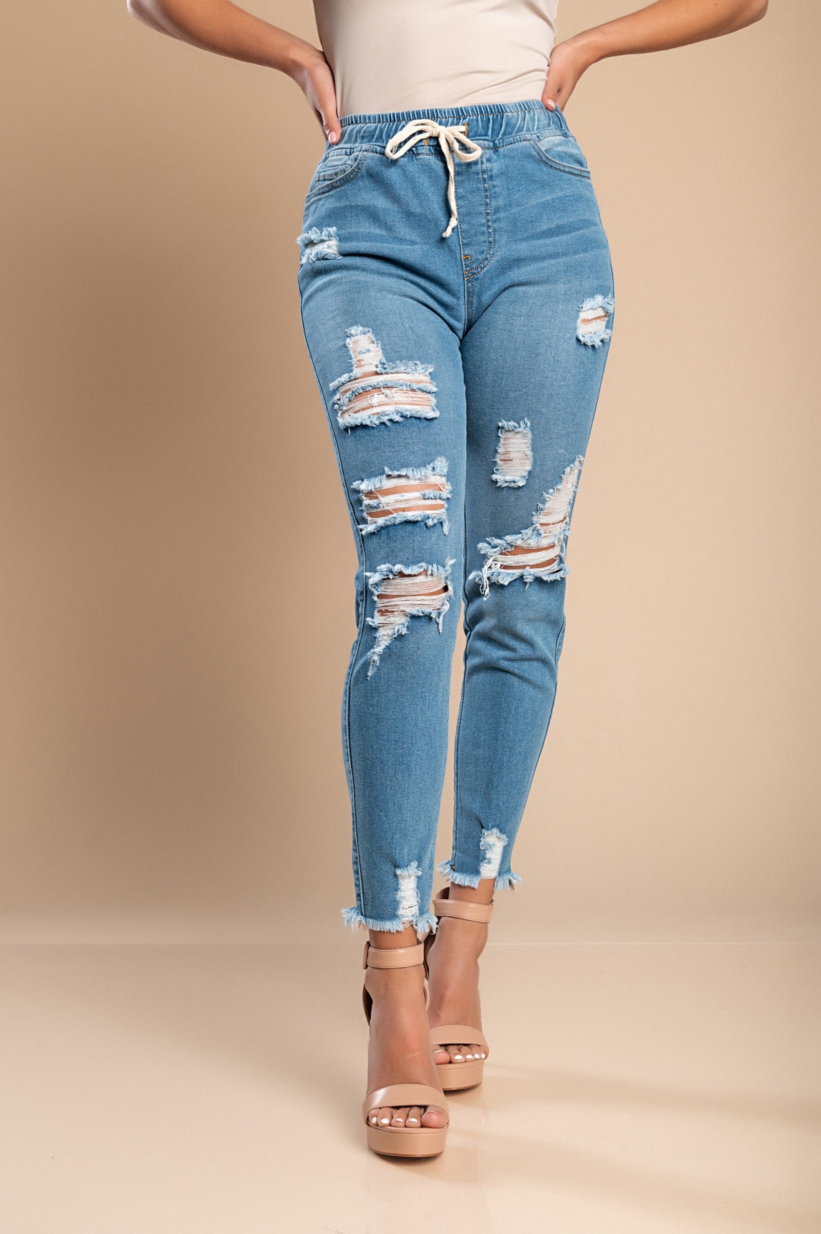 Sky blue high-waisted tight jeans with fashionable slits and ripped edges, featuring front and back pockets.