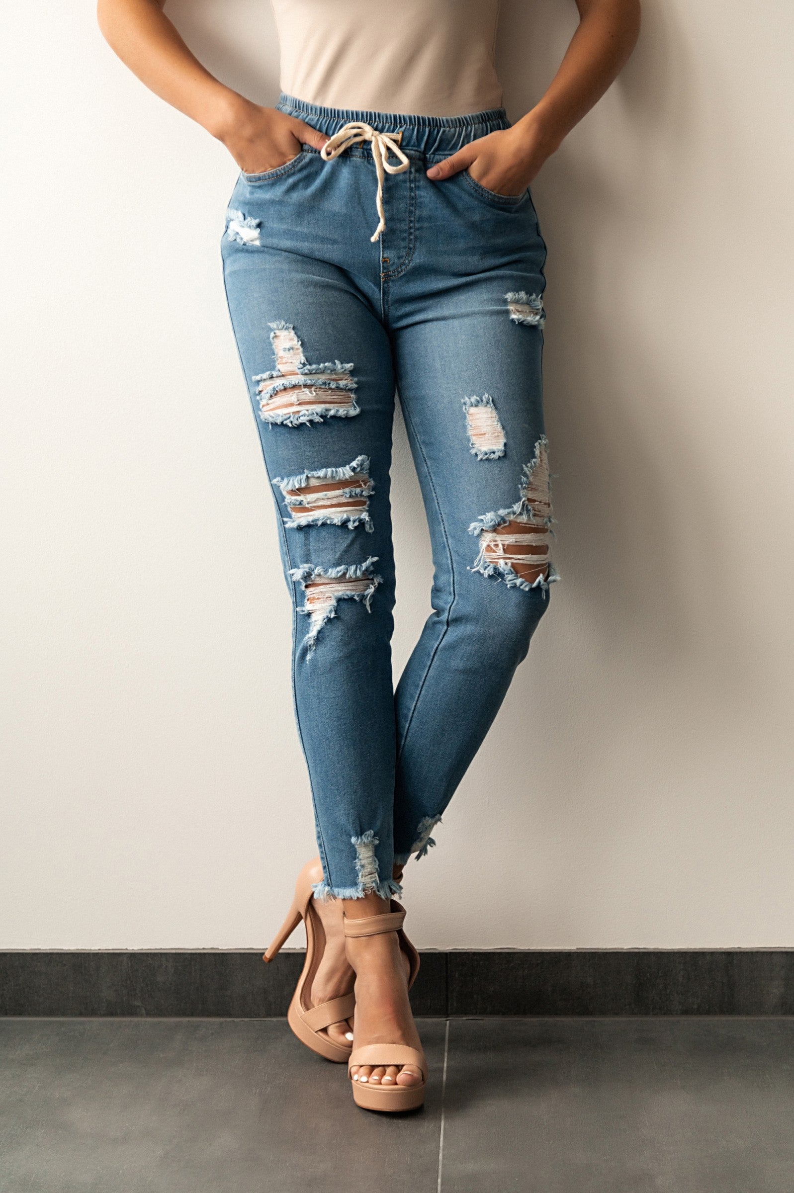 Sky blue tight jeans with high waist and fashionable slits, featuring ripped edges and pockets.