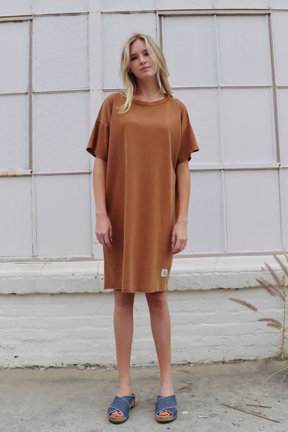 A relaxed fit Topanga Dress in saddle color, made from 100% organic cotton, displayed on a mannequin with sandals and a tote.