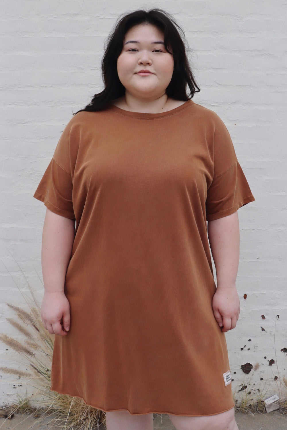 A relaxed fit Topanga Dress in saddle color, made from 100% organic cotton, displayed on a mannequin with sandals and a tote.