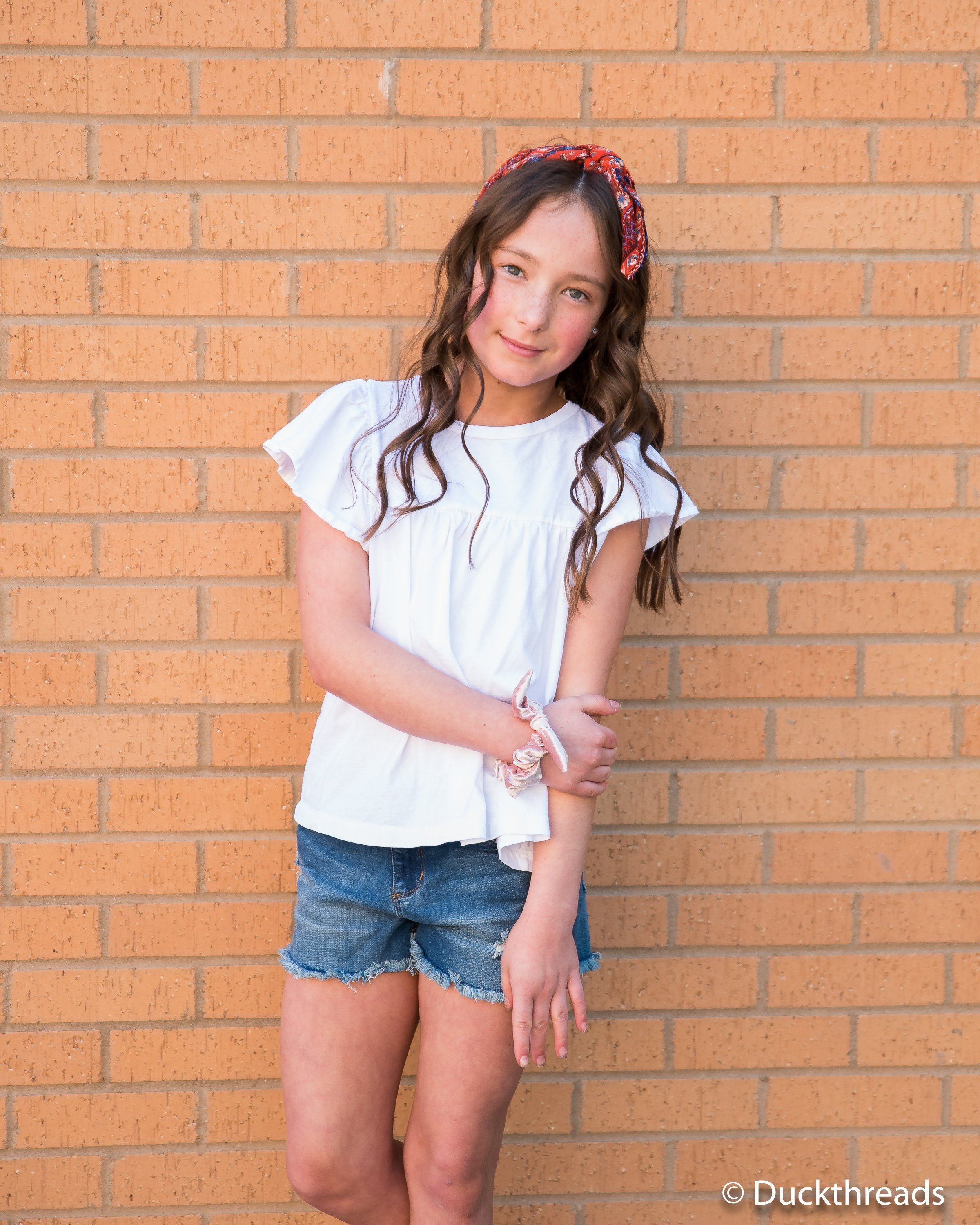 Tractr Dark Distressed Denim Shorts for Girls featuring a frayed hem and five pockets, styled with a casual tee.