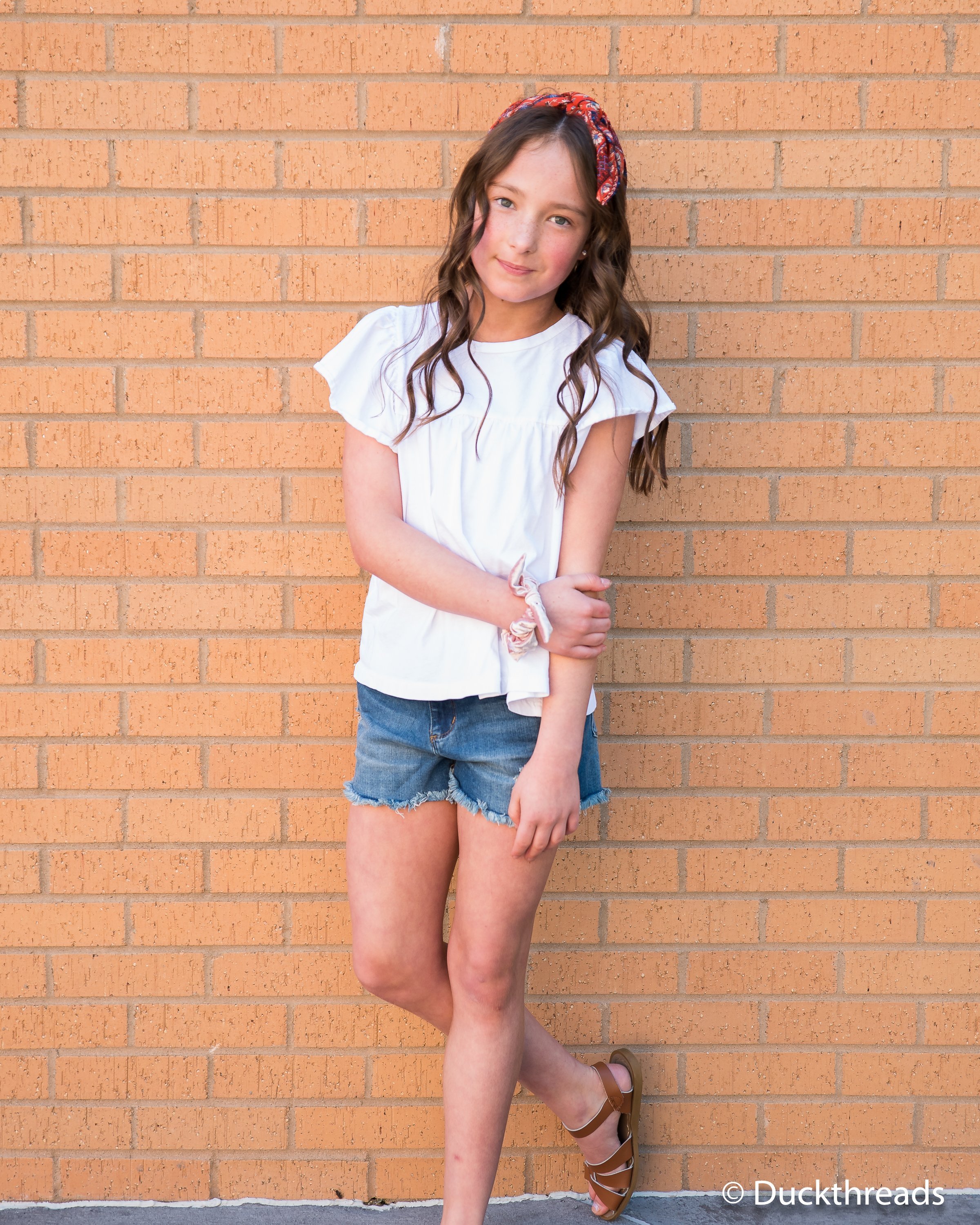 Tractr Dark Distressed Denim Shorts for Girls featuring a frayed hem and five pockets, styled with a casual tee.