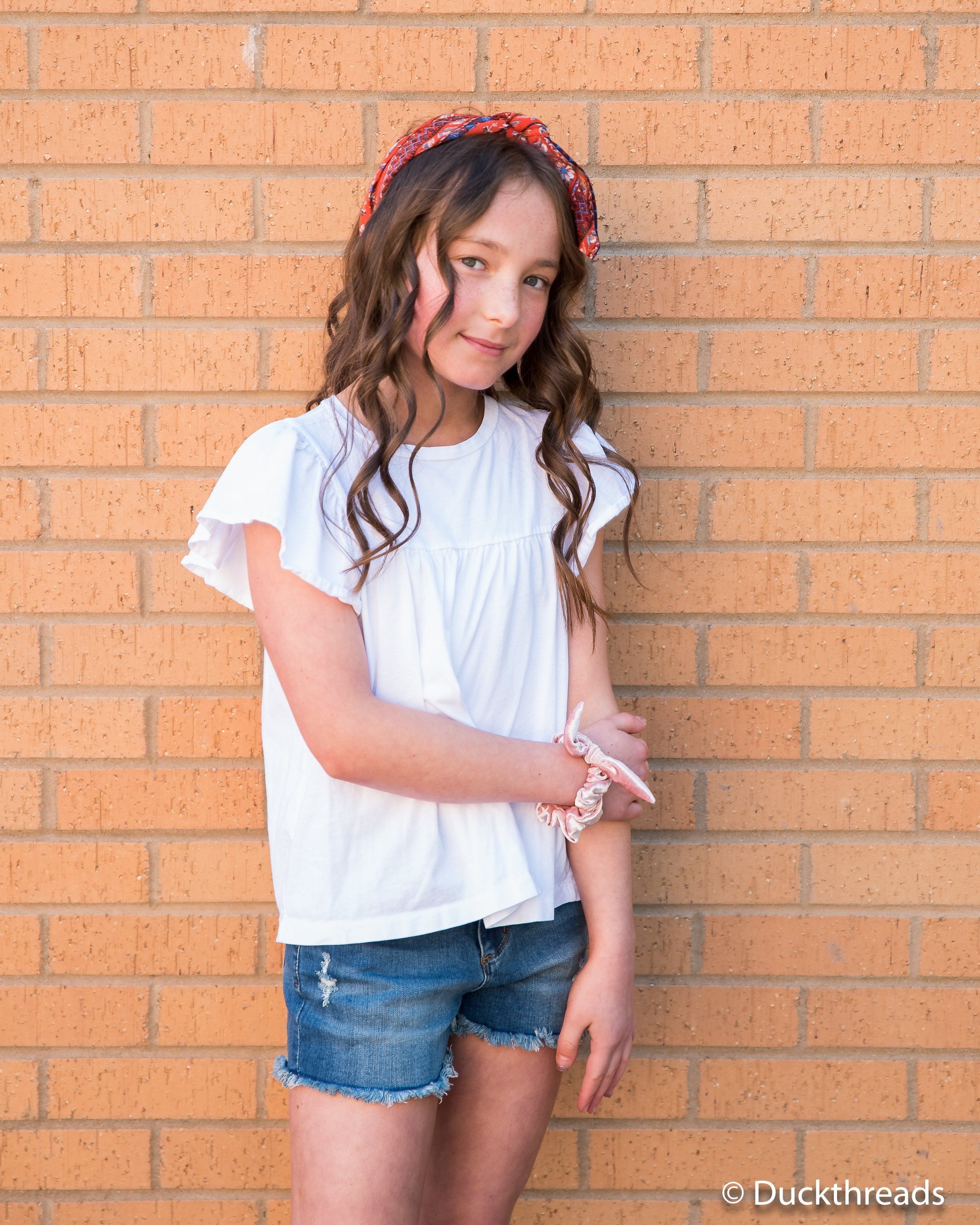 Tractr Dark Distressed Denim Shorts for Girls featuring a frayed hem and five pockets, styled with a casual tee.