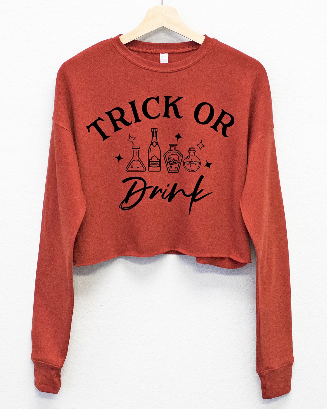 Trick or Drink Fleece Cropped Sweatshirt in black and burnt orange, featuring a playful Halloween design.