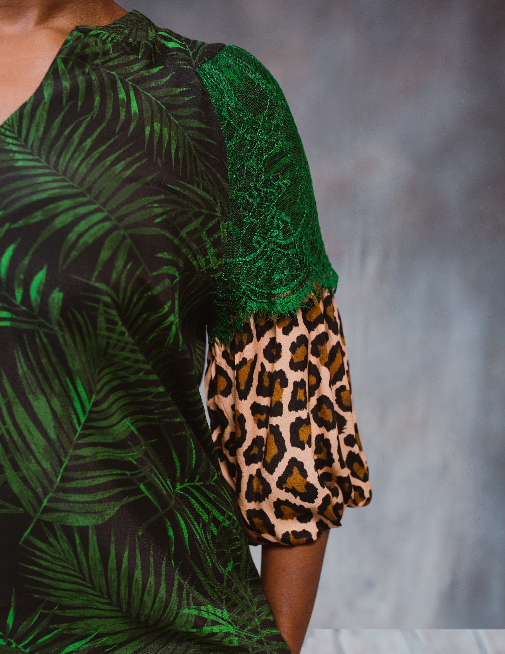 A stylish Tropical Print Top featuring a subtle tropical design, lace accents, and statement sleeves, perfect for various occasions.