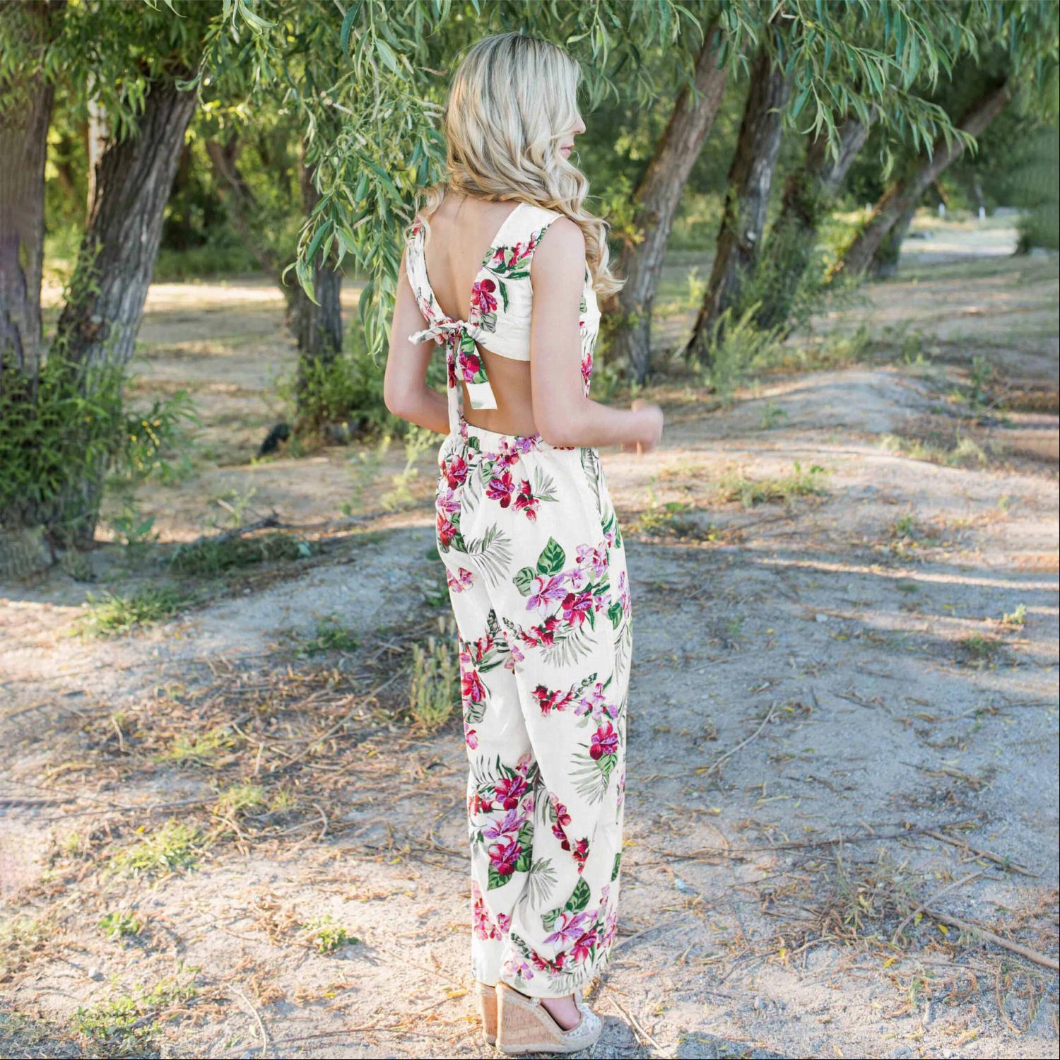 A stylish Tropical Tie Back Jumpsuit featuring a vibrant floral pattern, deep V back, and wide leg design, perfect for summer outings.