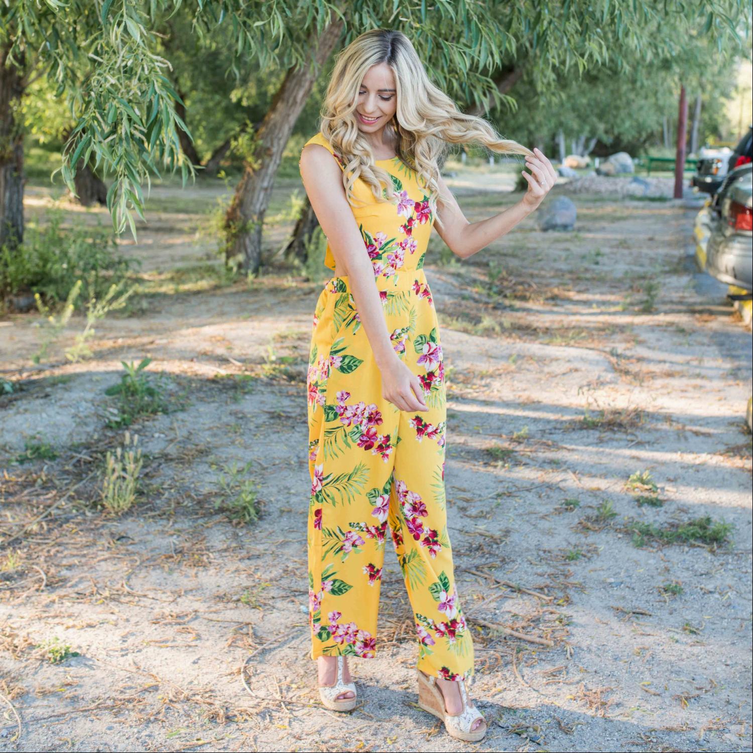 A stylish Tropical Tie Back Jumpsuit featuring a vibrant floral pattern, deep V back, and wide leg design, perfect for summer outings.