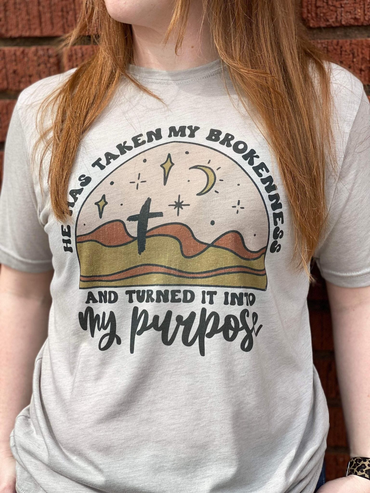 A stylish unisex apparel featuring the phrase 'Turned My Brokenness Into My Purpose' in vibrant colors, made from a soft poly-cotton blend.