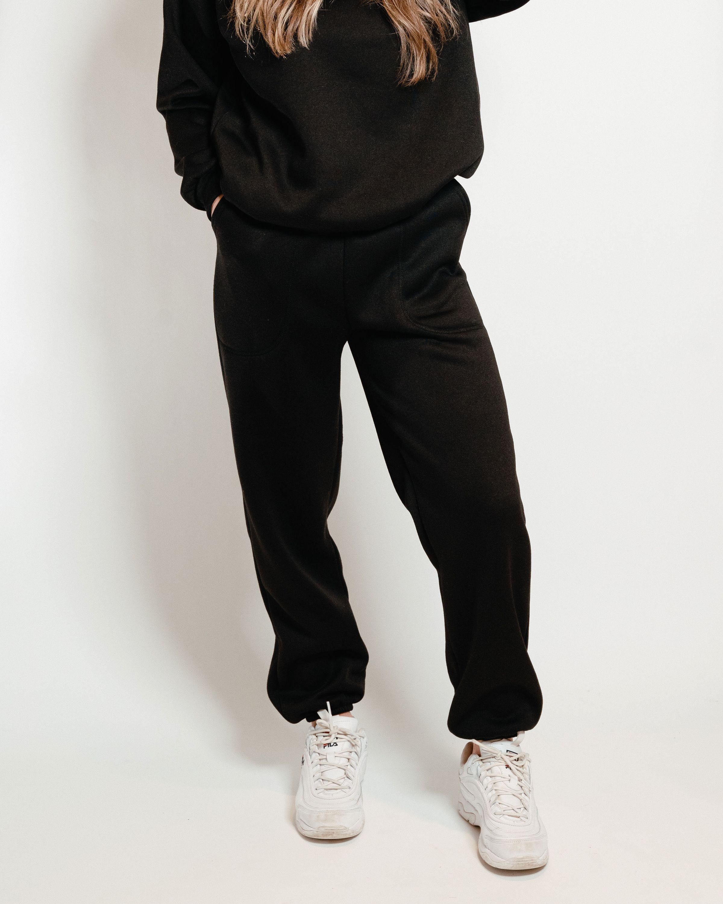 A pair of black unisex sweatpants, showcasing a soft interior and gender-neutral design, perfect for lounging or casual outings.