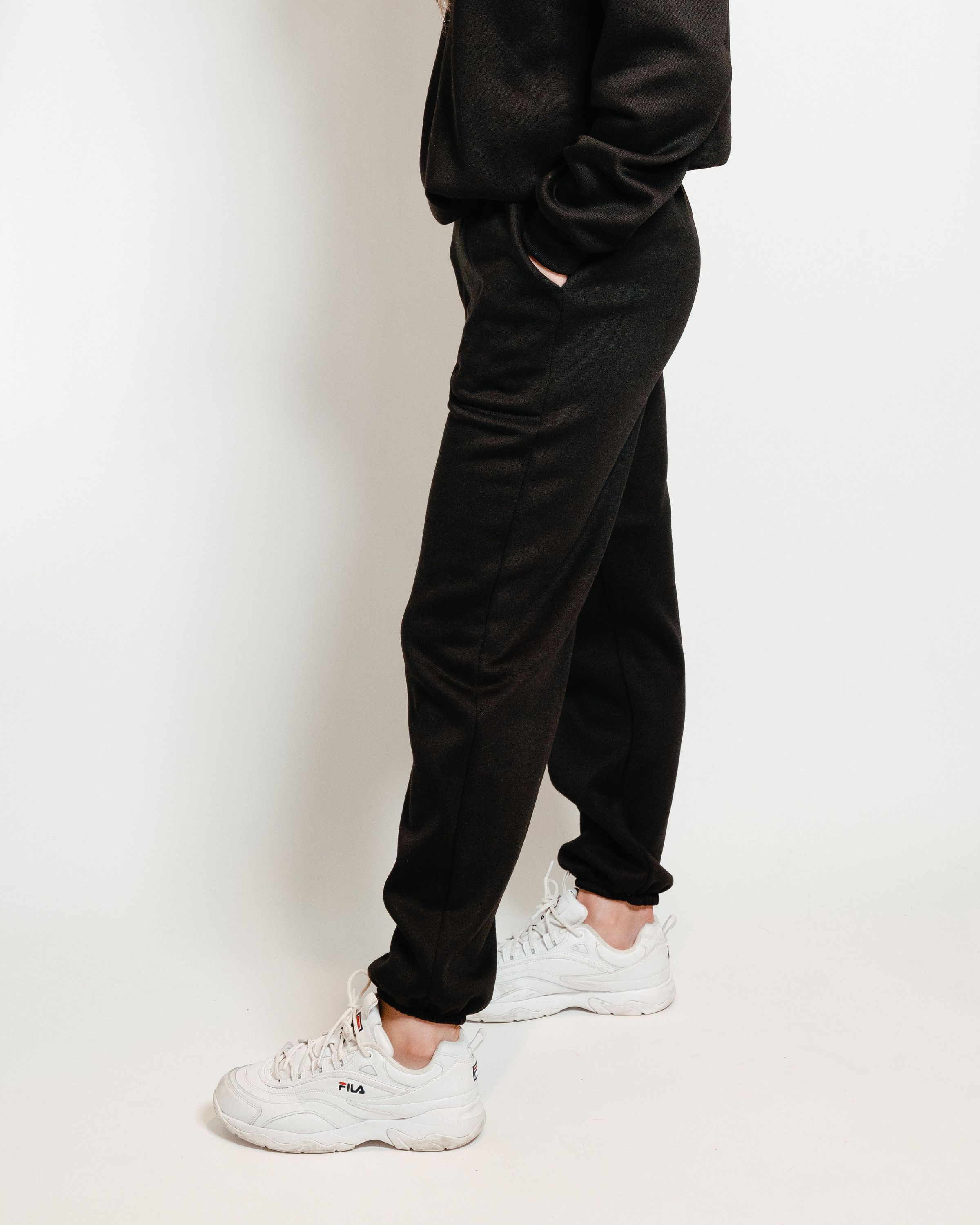 A pair of black unisex sweatpants, showcasing a soft interior and gender-neutral design, perfect for lounging or casual outings.