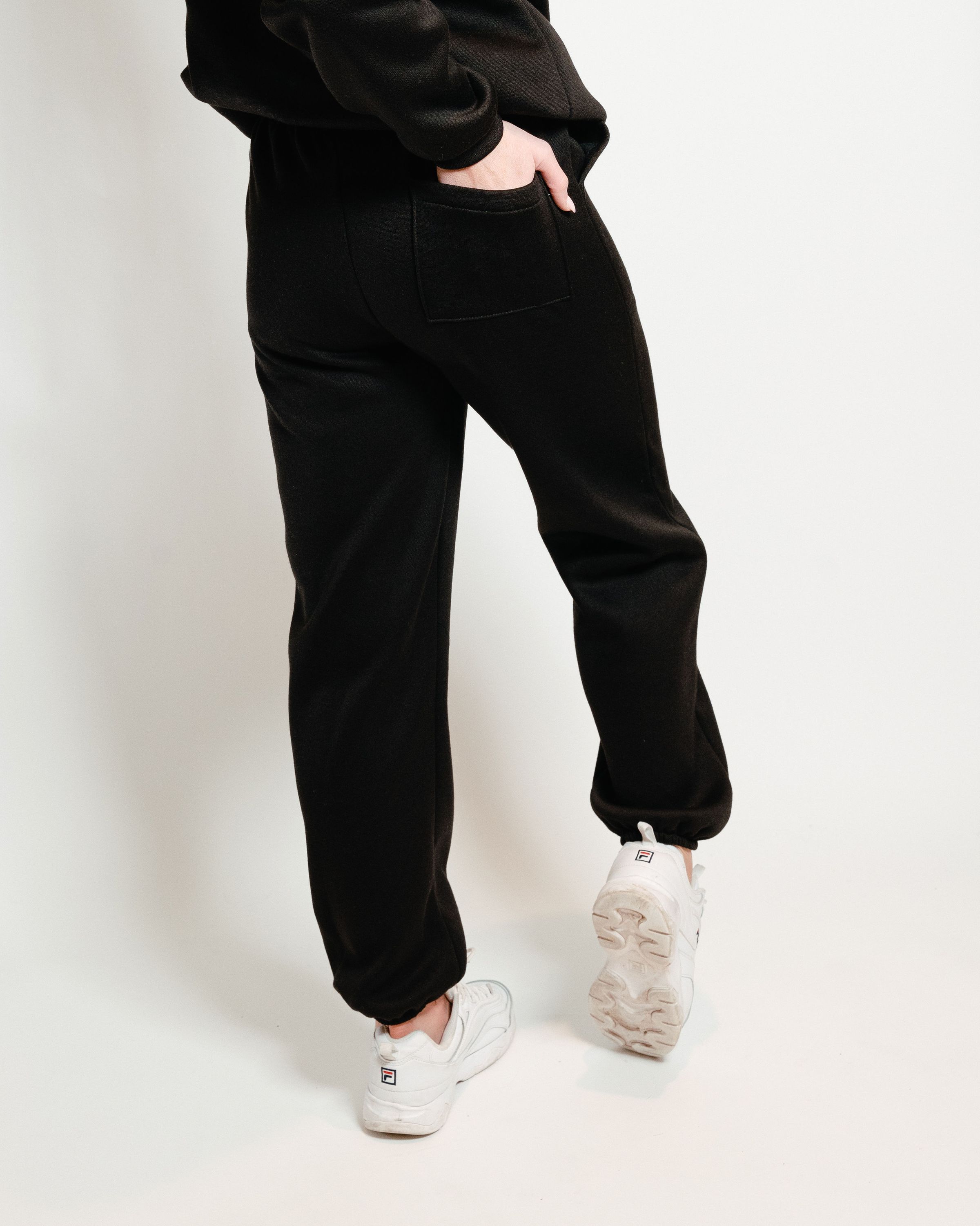 A pair of black unisex sweatpants, showcasing a soft interior and gender-neutral design, perfect for lounging or casual outings.