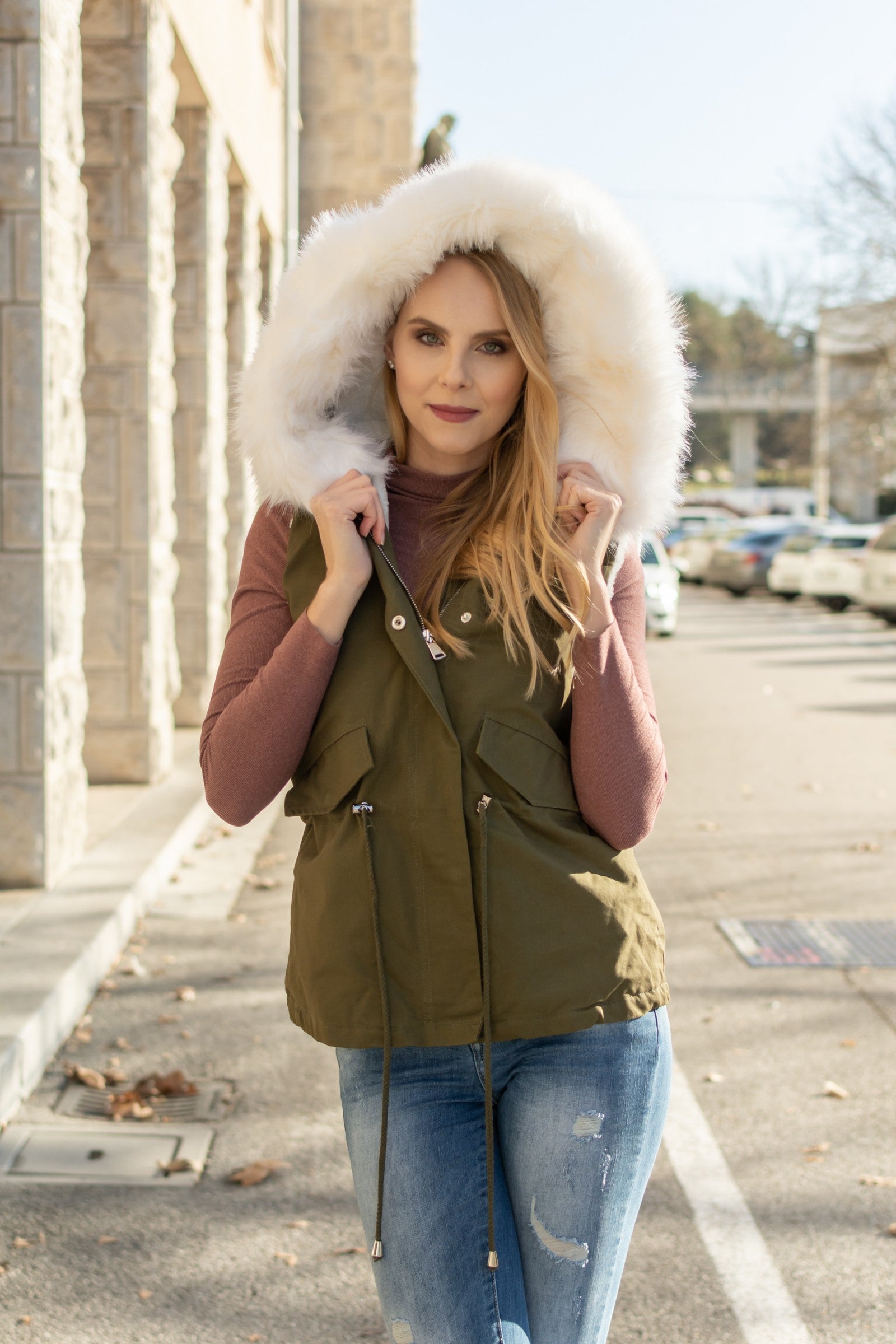 Olive white vest with rich faux fur hood and warm lining, featuring front pockets and adjustable waist drawstring.