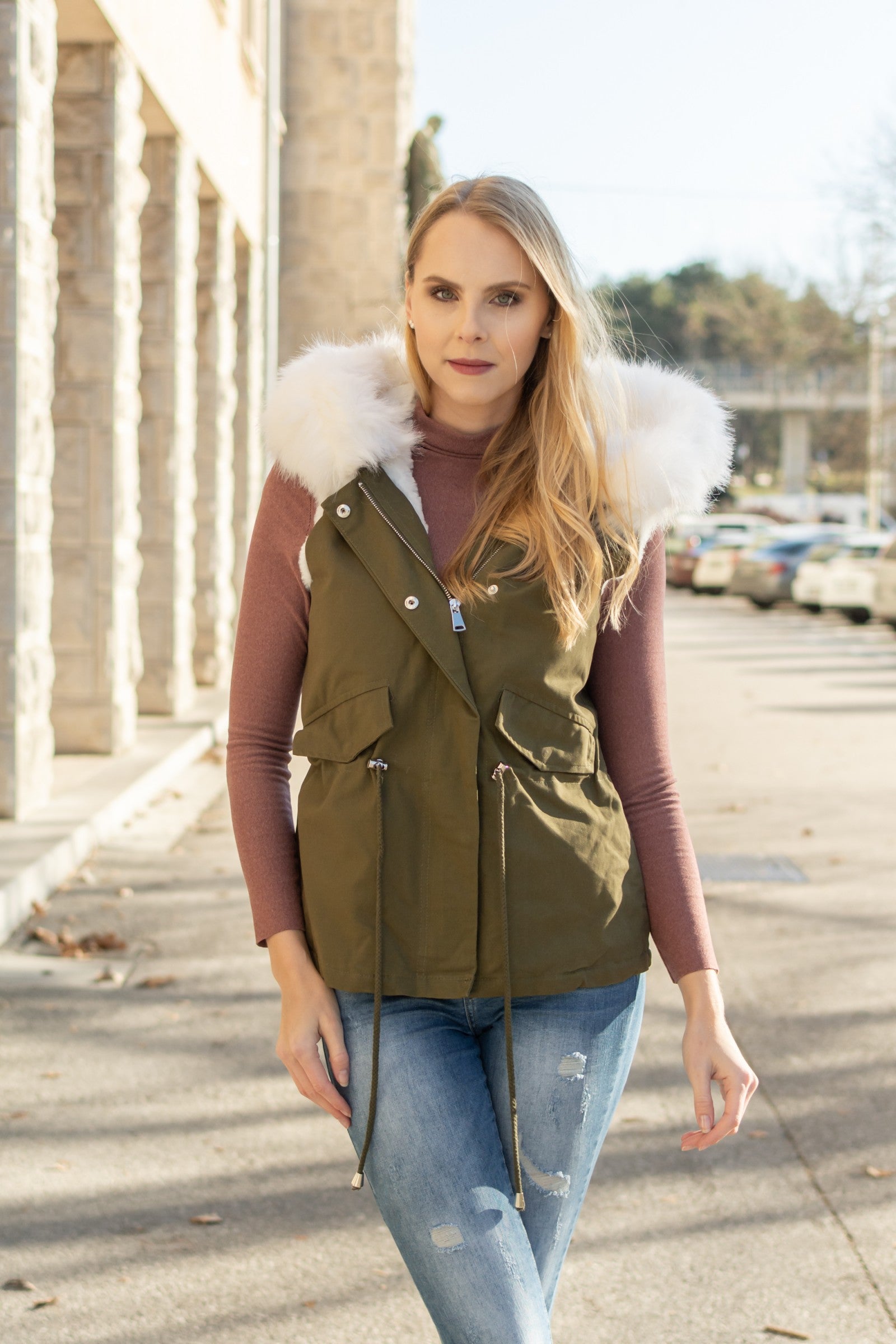 Olive white vest with rich faux fur hood and warm lining, featuring front pockets and adjustable waist drawstring.