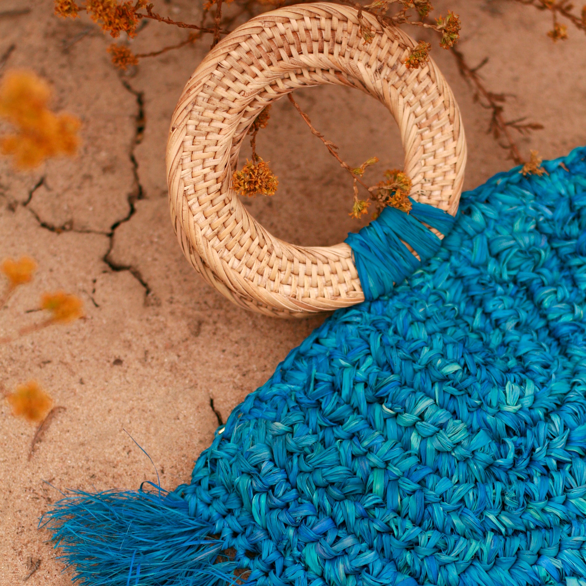 Warrior Raffia Straw Bag in Blue, handcrafted with natural Raffia straw, featuring fringes and a stylish rattan handle.