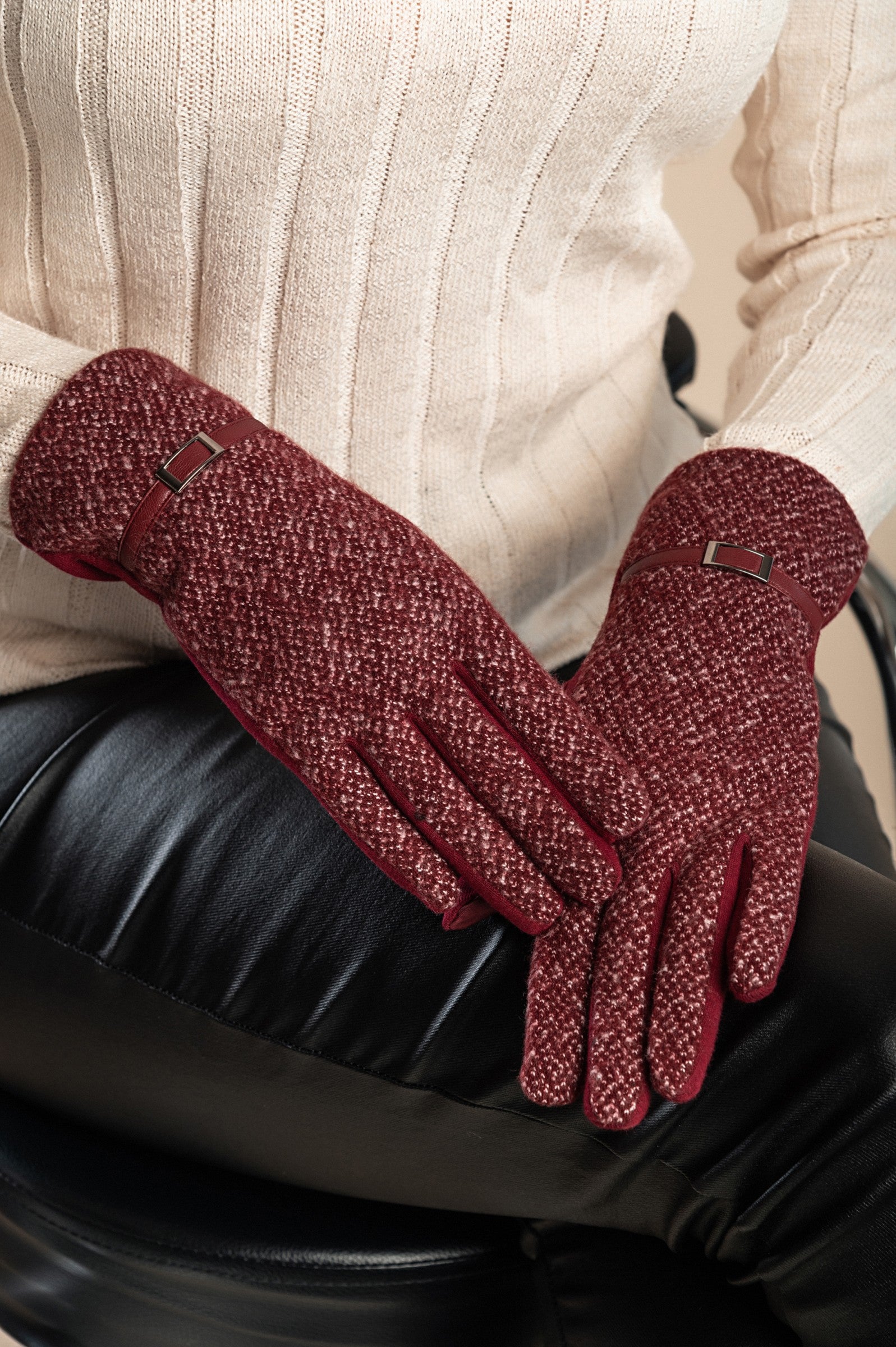 A pair of burgundy warm gloves with a decorative strap on the wrist, showcasing a soft and padded texture, perfect for winter wear.