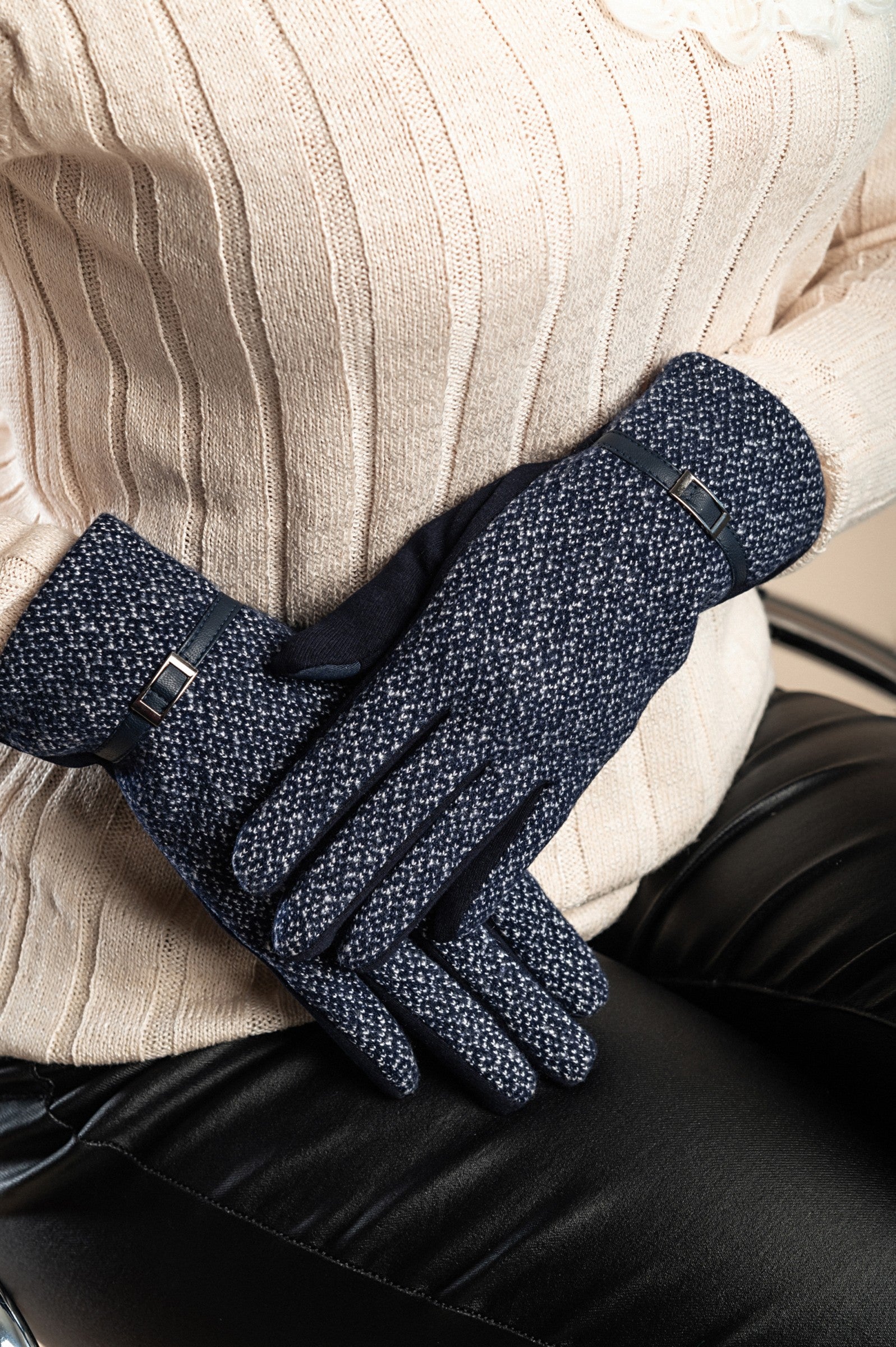 A pair of dark blue warm gloves with a decorative strap on the wrist, showcasing their soft and padded texture.