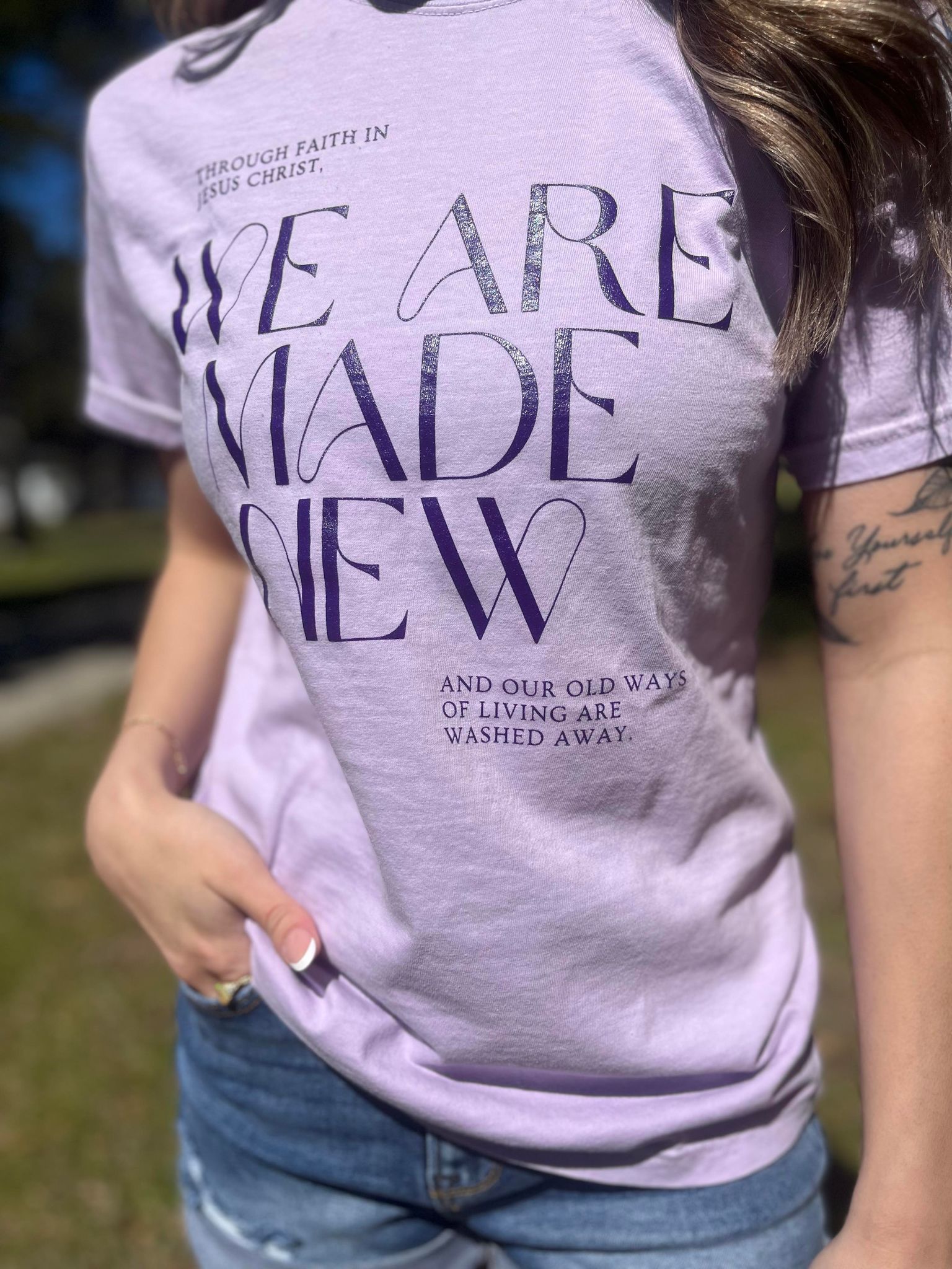 A stylish monochrome purple tee with the text 'We Are Made New' printed on it, showcasing a comfortable fit.