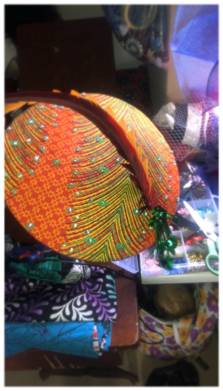 A stylish wide brim hat made from vibrant Ankara fabric, featuring elegant embellishments and Swarovski crystals, perfect for any occasion.