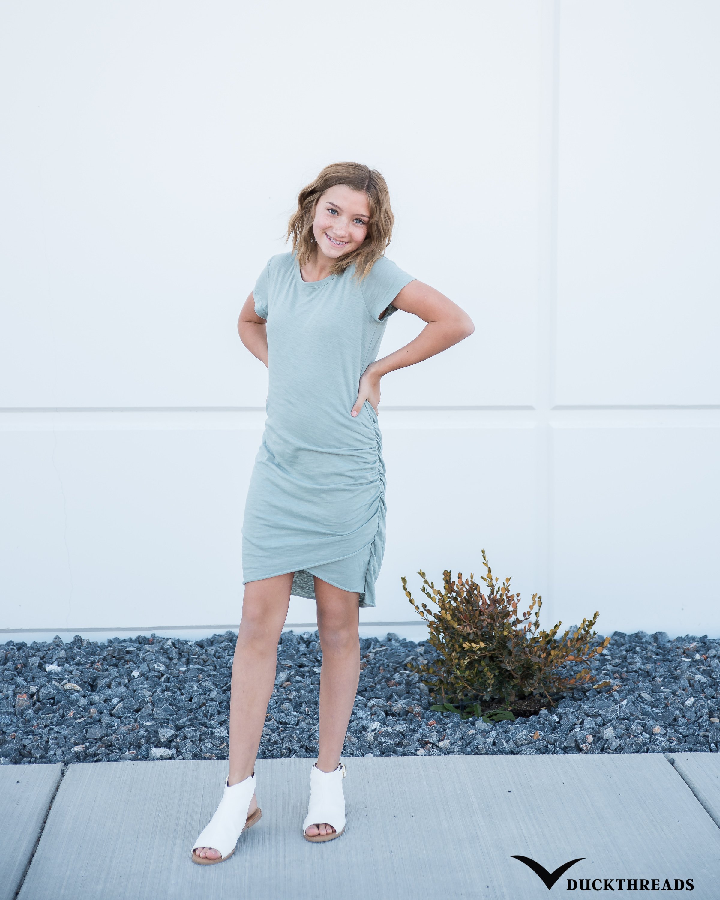 Woman's casual tee shirt dress in Steel Blue with tulip hemline, featuring ruching at the waist, perfect for versatile styling.