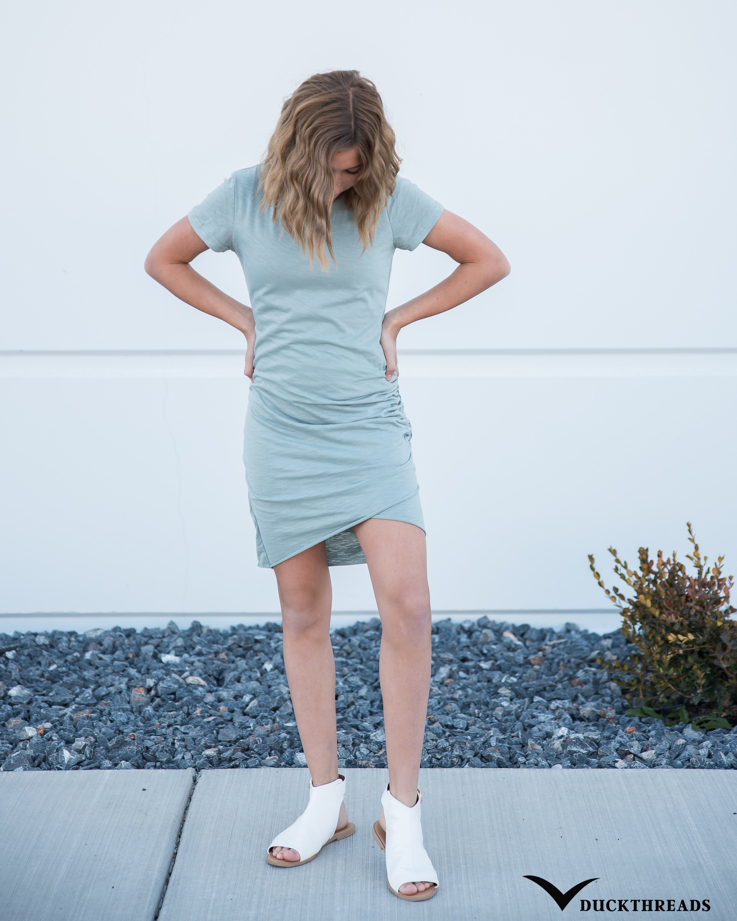 Woman's casual tee shirt dress in Steel Blue with tulip hemline, featuring ruching at the waist, perfect for versatile styling.