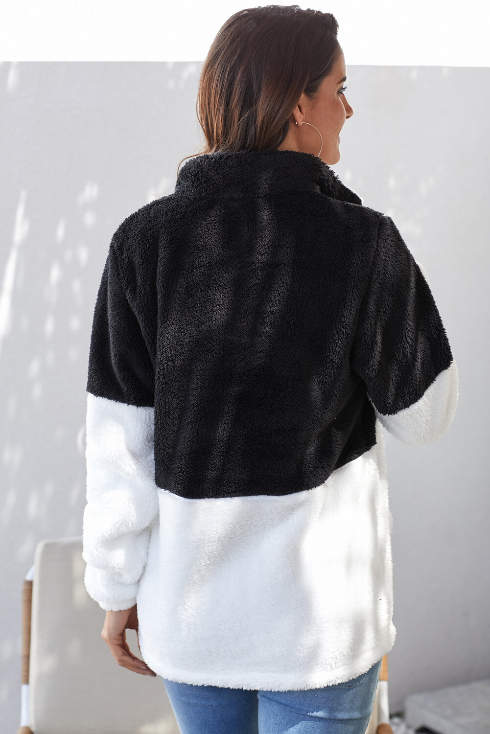 Women wearing a black and white oversized fluffy fleece pullover with a zip neck, showcasing its cozy design and kangaroo pocket.