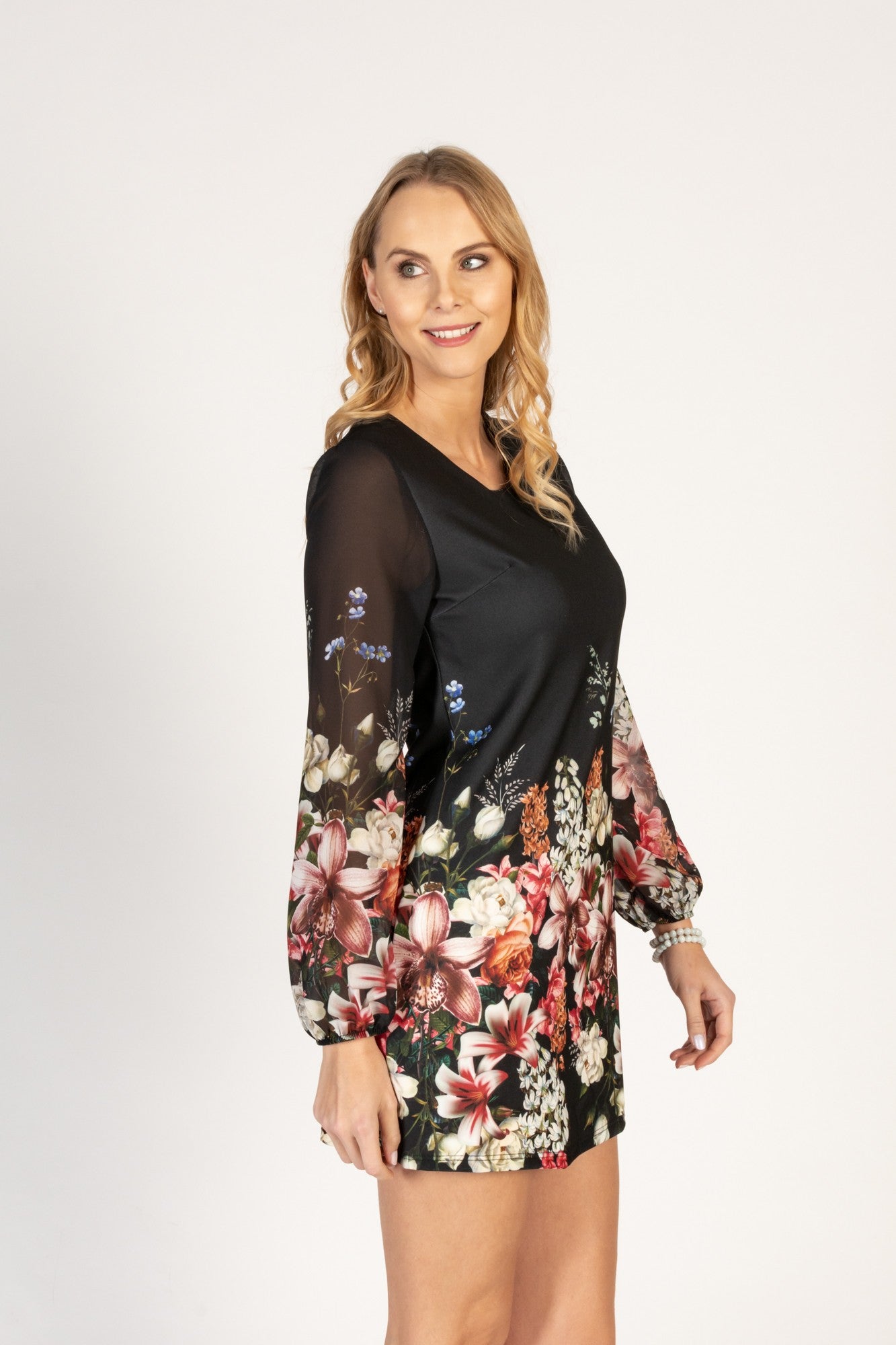 WOMEN TUNIC SIENNA - FLOWERS featuring a vibrant floral print, long translucent sleeves, and a back zipper, made from lightweight fabric.