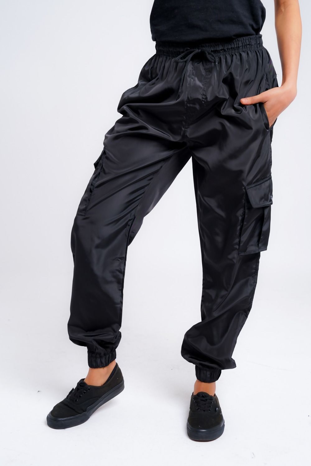 A pair of stylish women's black cargo trousers with cuffs, showcasing pockets and a modern fit.