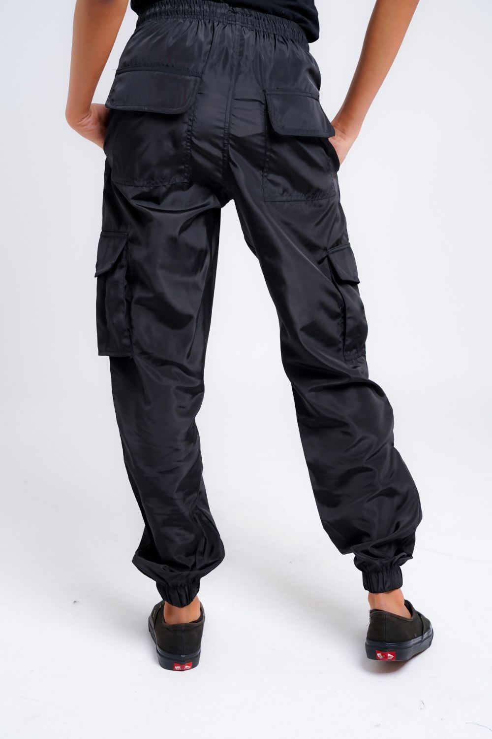 A pair of stylish women's black cargo trousers with cuffs, showcasing pockets and a modern fit.