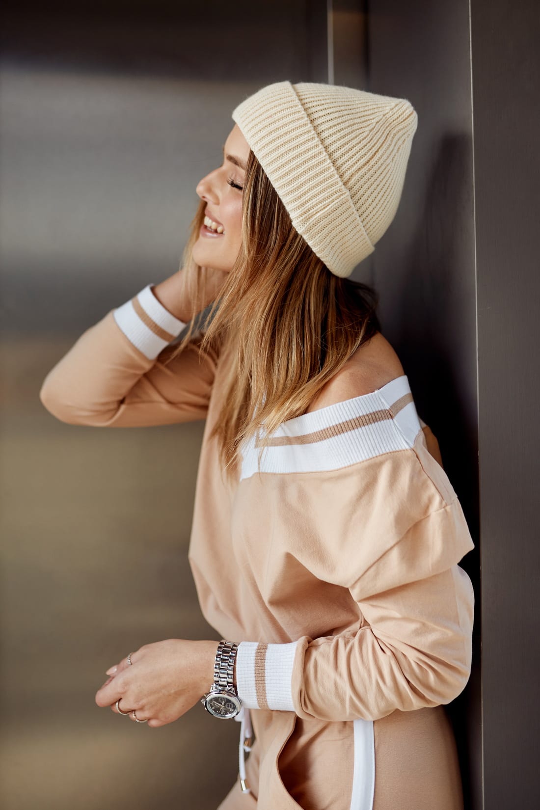 Light beige women's cap with a rolled-up cuff and drawstring, made from elastic sweater fabric.