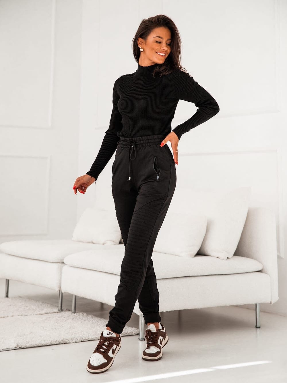 Women's black sweatpants with decorative stitching and zippered pockets, featuring an elastic waist and cuffs.