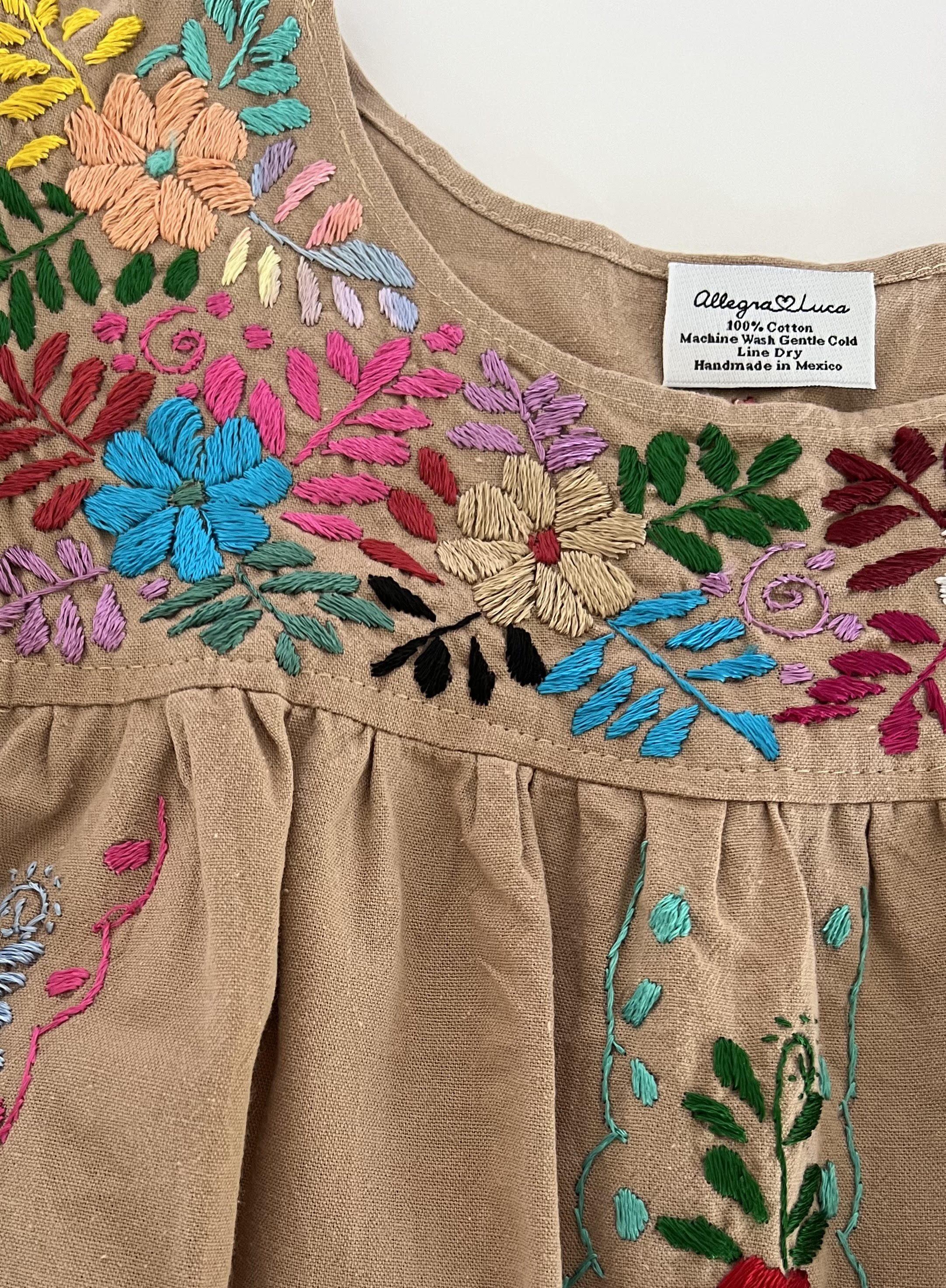 Women's tan blouse with multicolor hand embroidery and flutter sleeves, made from organic cotton.