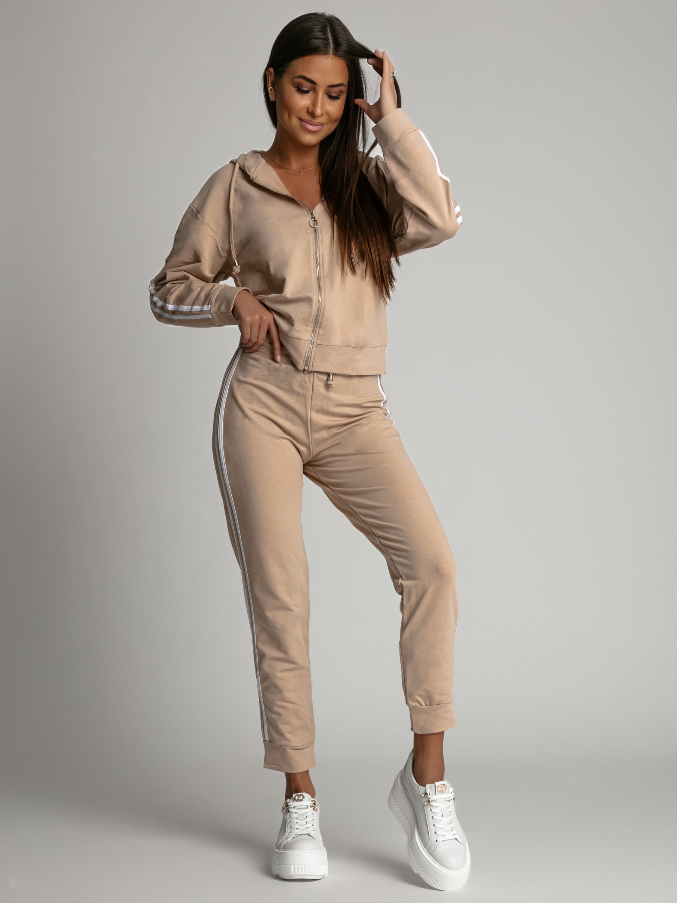 Women's beige tracksuit set featuring a zip-up hoodie and elastic waist pants with white stripes, perfect for casual and sporty looks.