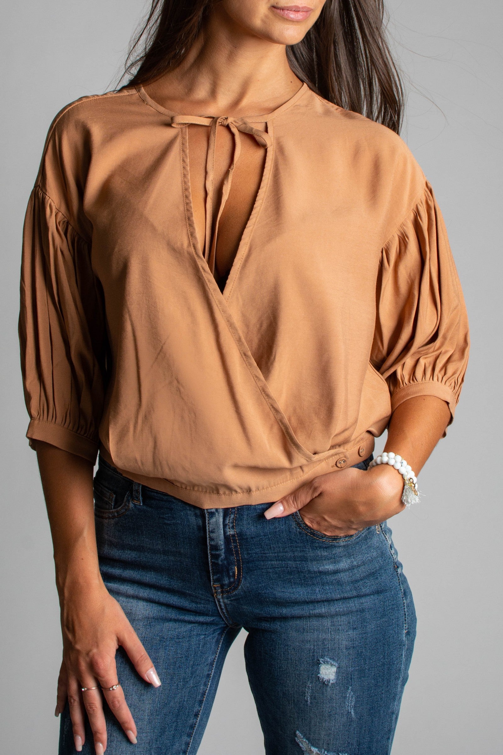 Khaki wrap blouse with short gathered sleeves and tie detail in the décolleté area, showcasing elegant design and soft fabric.