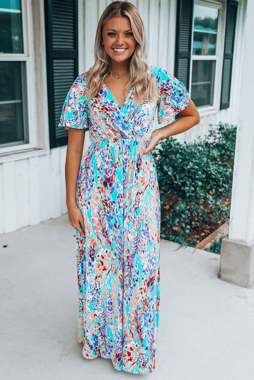 A stylish Wrap V Neck Floral Maxi Dress featuring a vibrant floral print, flutter sleeves, and a flattering wrap design, perfect for summer occasions.