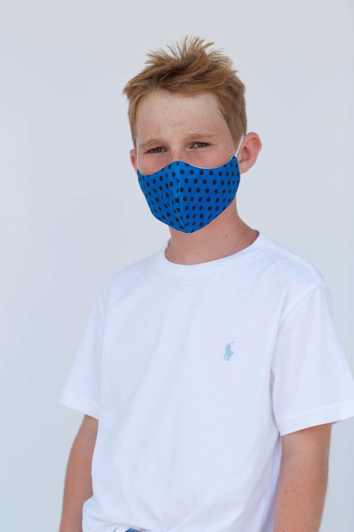 Youth Blue Polka Face Mask featuring a vibrant blue polka dot design, made of three layers for comfort and breathability.