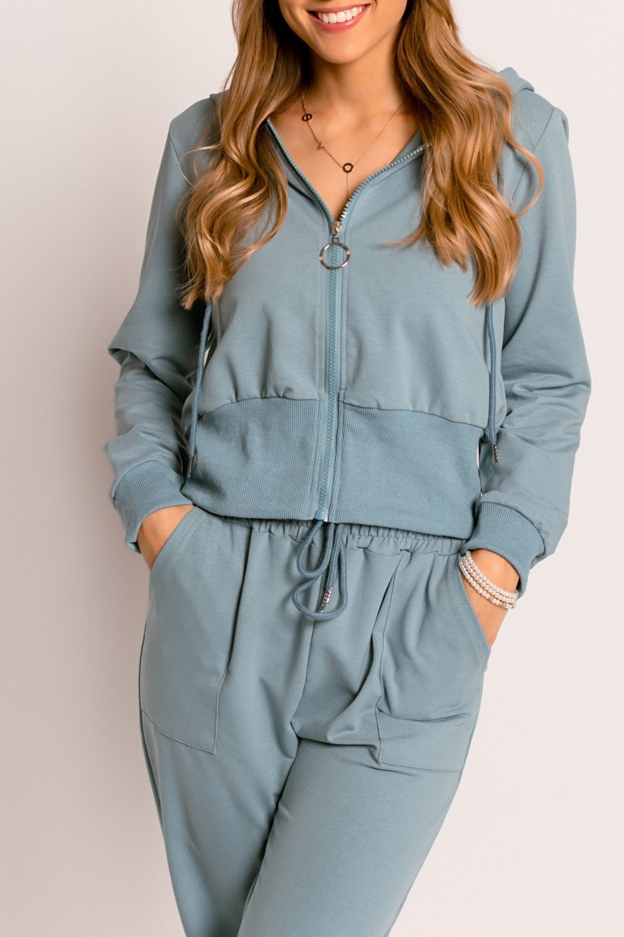 Zipped sports shirt Trepita in blue with long sleeves, drawstring hood, and front zipper closure, showcasing its stylish and comfortable design.